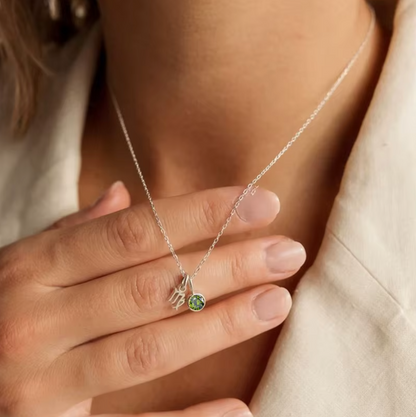 Astrological Birthstone Pendant on model. Crafted from stainless steel and available in luxurious 14K gold, sleek silver, or rose gold plating, this necklace features your zodiac sign alongside your birthstone.