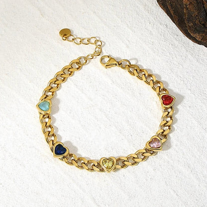 Caeli Charmed Hearts Bracelet. This stainless steel piece features five vibrant zircon stones nestled within heart charms in a bold, flat cuban chain link.