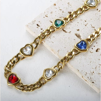 Caeli Charmed Hearts Bracelet. This stainless steel piece features five vibrant zircon stones nestled within heart charms in a bold, flat cuban chain link.