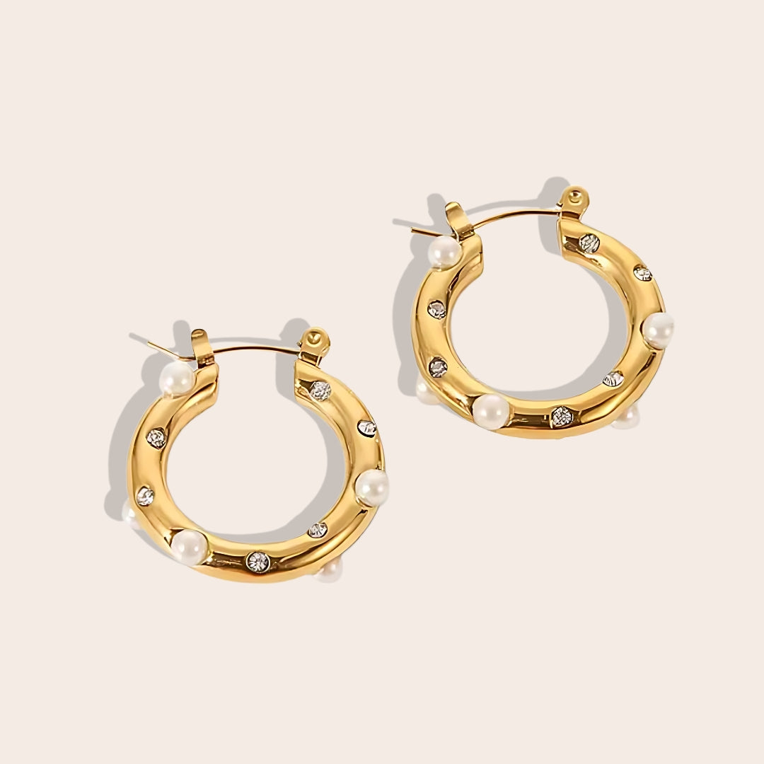 Caia Classic Studded Huggies. These exquisite earrings, crafted from 18K gold plated stainless steel, feature a dazzling array of zircon stones or pearls.