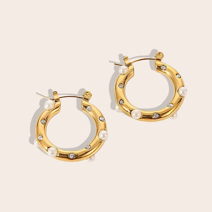 Caia Classic Studded Huggies. These exquisite earrings, crafted from 18K gold plated stainless steel, feature a dazzling array of zircon stones or pearls.