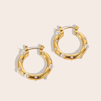 Caia Classic Studded Huggies. These exquisite earrings, crafted from 18K gold plated stainless steel, feature a dazzling array of zircon stones or pearls.