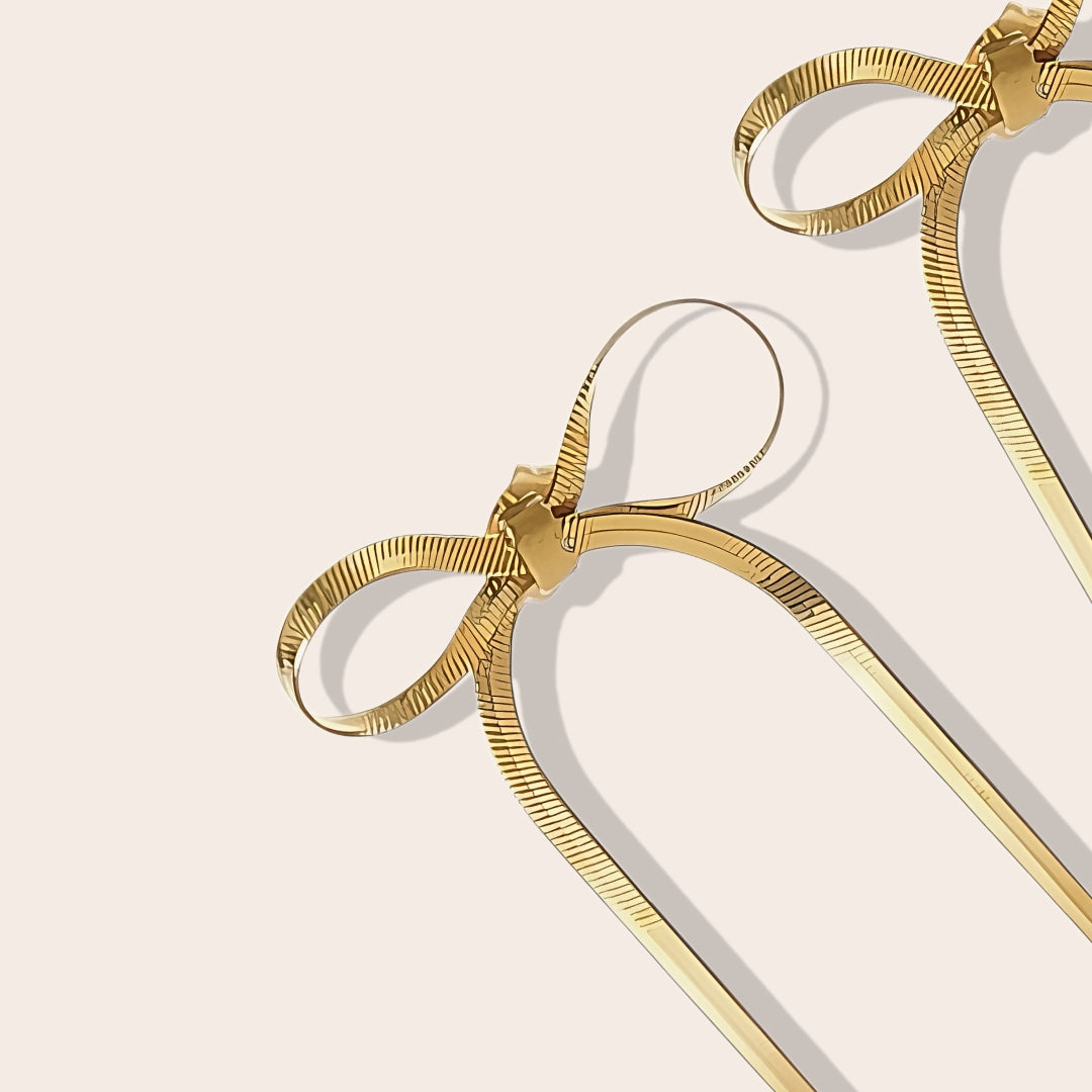 Close up of Coquette Bow Drop Earrings in gold. Constructed from lasting stainless steel.