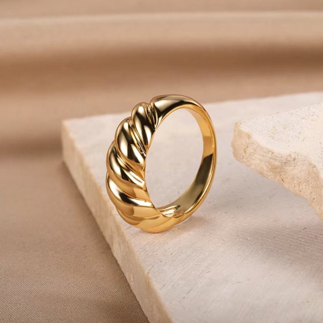 Crafted from durable stainless steel and luxuriously plated with 18K gold, this chunky ring features a unique twist design. Lifestyle shot.