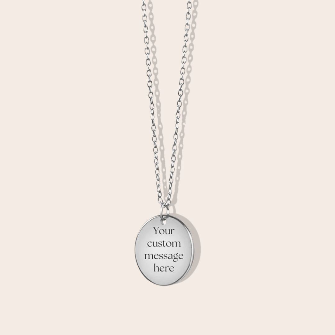 Personalized initials necklace studio shot. Silver coin shape with silver chain. Back side with custom message engraving.