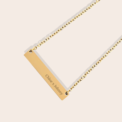 Customizable couples name necklace with front engraving and special message for back engraving. Gold, horizontal bar orientation. Close up.