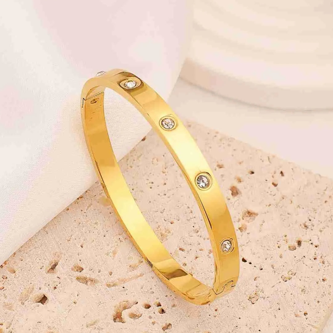 Harlow Hinged Bangle in gold, a dazzling fusion of sleek stainless steel and twinkling zircon stones. Lifestyle shot.