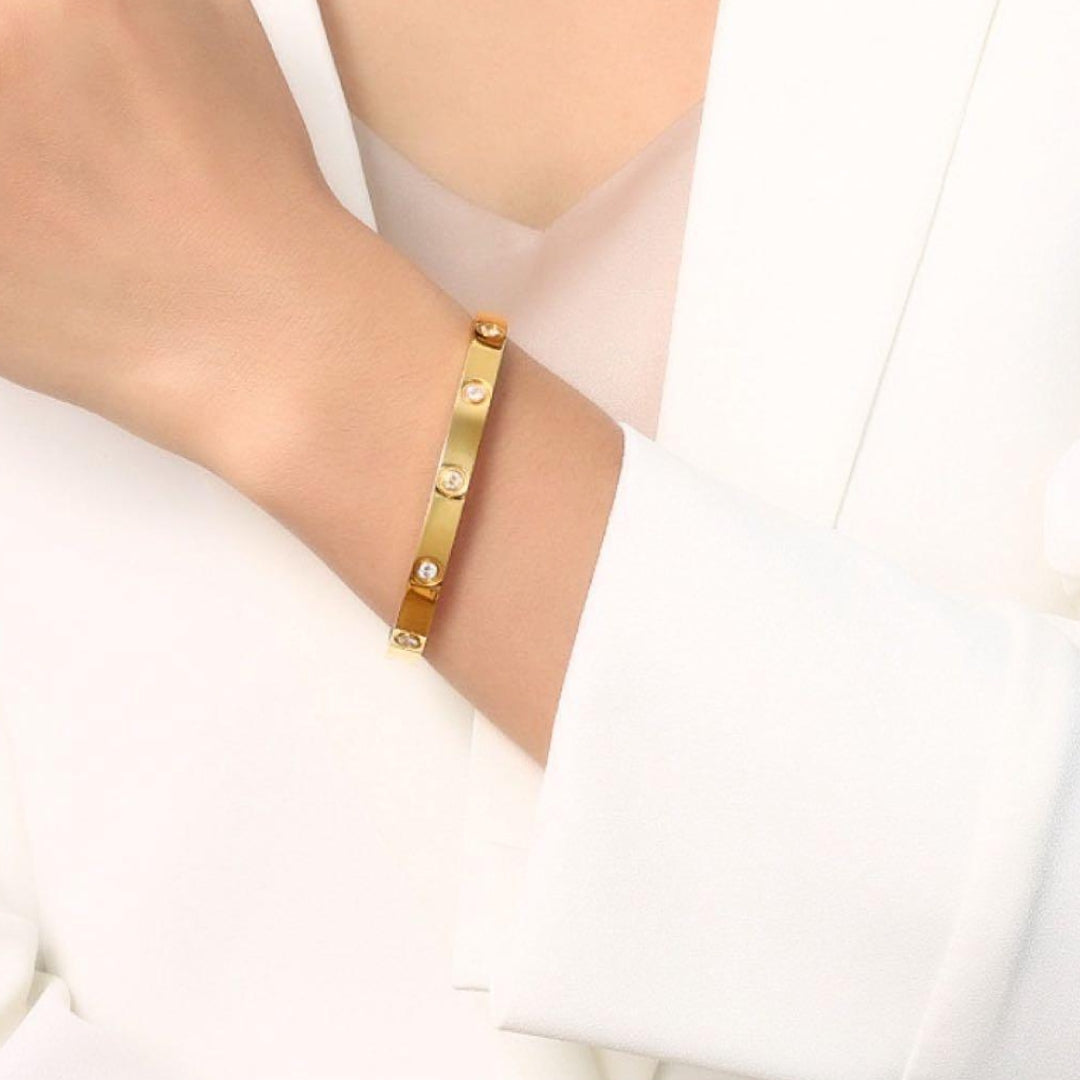 Harlow Hinged Bangle in gold, on model, a dazzling fusion of sleek stainless steel and twinkling zircon stones.