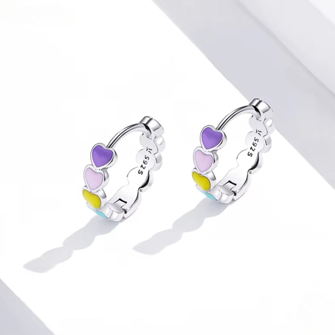 Heart-to-Heart Huggies. Crafted from premium 925 sterling silver, these earrings feature a heart-to-heart design, beautifully accented with splashes of color. On model.