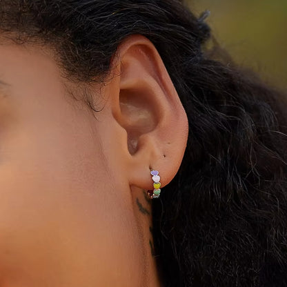 Heart-to-Heart Huggies. Crafted from premium 925 sterling silver, these earrings feature a heart-to-heart design, beautifully accented with splashes of color. On model.