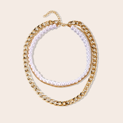 Lila Layered Trio Necklace. A lustrous pearl, a delicate cable chain, and a bold curb chain, all lavishly plated in 18K gold.