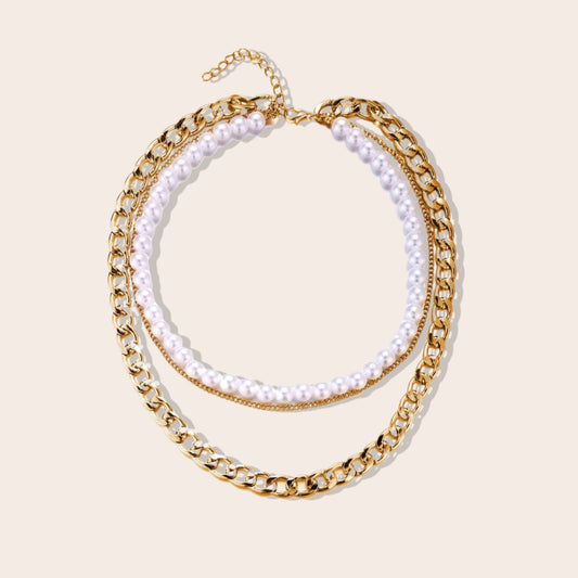 Lila Layered Trio Necklace. A lustrous pearl, a delicate cable chain, and a bold curb chain, all lavishly plated in 18K gold.