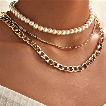 Lila Layered Trio Necklace. A lustrous pearl, a delicate cable chain, and a bold curb chain, all lavishly plated in 18K gold.