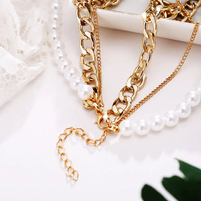 Lila Layered Trio Necklace. A lustrous pearl, a delicate cable chain, and a bold curb chain, all lavishly plated in 18K gold.