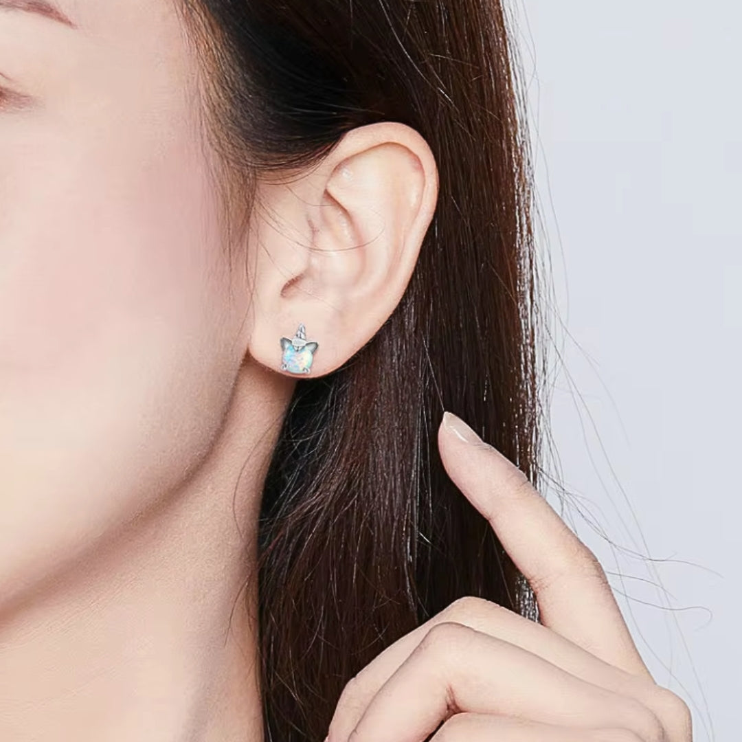 Opal Unicorn Stud Earrings on model. Crafted from 925 sterling silver, plated with platinum, and adorned with shimmering white opals.