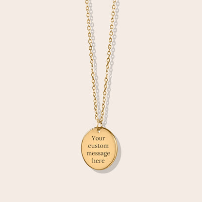 Personalized initials necklace studio shot. Gold coin shape with gold chain. Back side with custom message engraving.