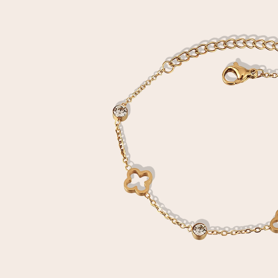 Close up of Quinn Quatrefoil Cutout Bracelet. This charming piece in gold features an intricate quatrefoil cutout design in lustrous gold plated stainless steel, accented by AAA zircon stones.