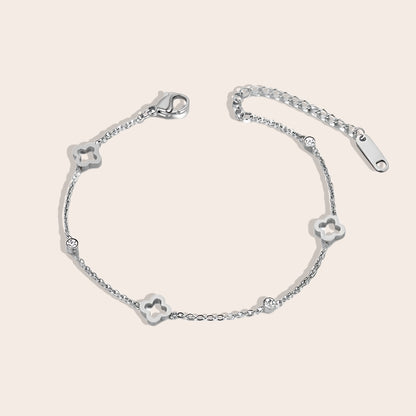 Quinn Quatrefoil Cutout Bracelet. This charming piece in silver features an intricate quatrefoil cutout design in lustrous gold plated stainless steel, accented by AAA zircon stones.