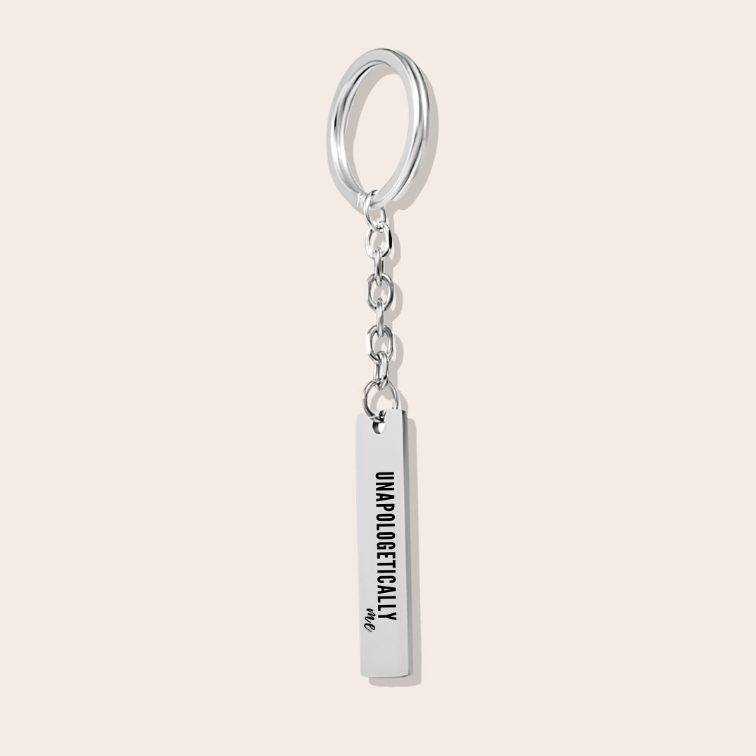 Vertical Bar Keychain - Unapologetically Me, in silver. Created from stainless steel and plated with 18K gold, this sleek piece features a laser-engraved affirmation.